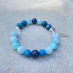 Cargar imagen en el visor de la galería, Beaded bracelet with blue and clear beads on a gray fabric background

